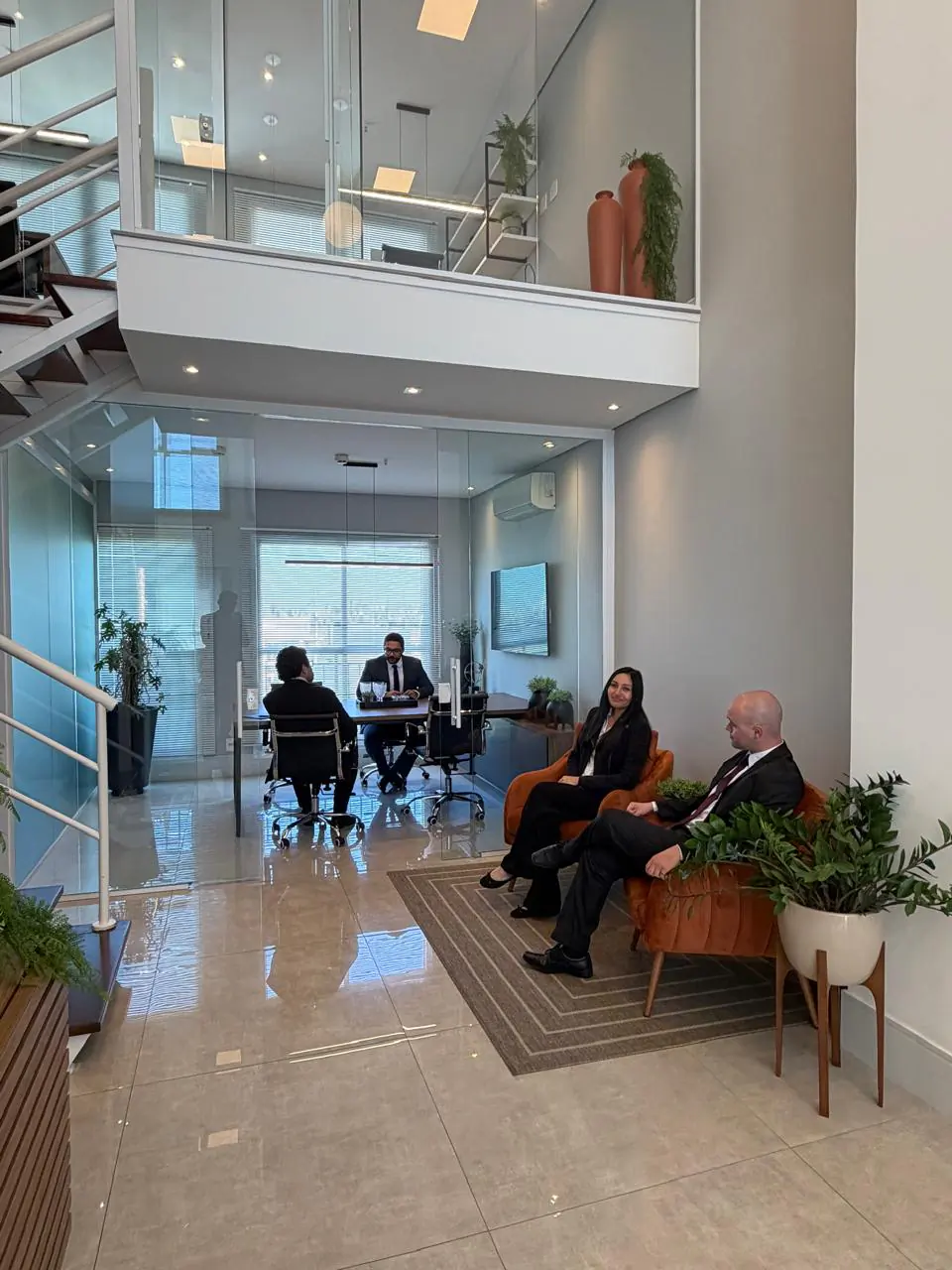 Hall de pé-direito duplo, com clientes aguardando e a sala de reunião ao fundo